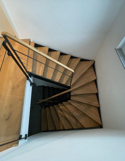 Escalier moderne bois métal type industriel avec limon en acier laqué, garde-corps en fer plat et finition main courante bois soudé et remplissage cables inox et verre en aprtie basse