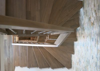 Strasbourg : escalier suspendu deux quart tournant sur plot inox avec balustres verticales et marche en hêtre teinté massif
