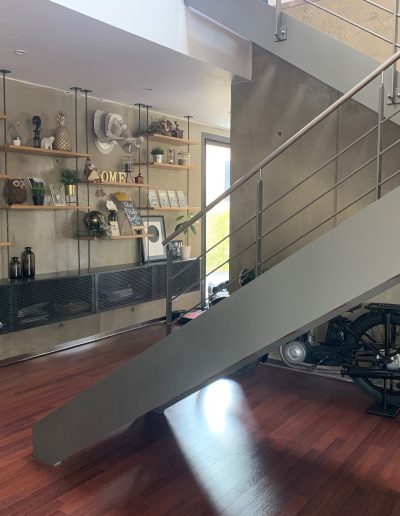 Escalier design industriel en acier gris avec marches en bois et garde-corps inox, poteaux plats et main courante ronde soudée. Escalier avec palier intérmédiaire