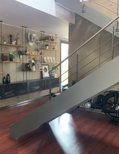 Escalier design industriel en acier gris avec marches en bois et garde-corps inox, poteaux plats et main courante ronde soudée. Escalier avec palier intérmédiaire