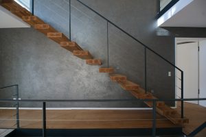 garde-corps rampant en acier plat laqué gris antracite et cable horizontal en inox autour d'une scalier autoporteur en bois