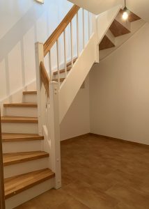 Escalier traditionnel en bois avec main courante et marches en chênes. Contre marche et limon laqué en blanc, ballustres bois