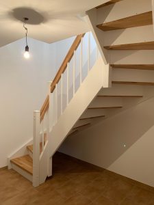 Escalier traditionnel en bois avec main courante et marches en chênes. Contre marche et limon laqué en blanc, ballustres bois