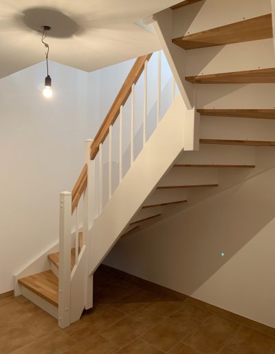 Escalier traditionnel en bois avec main courante et marches en chênes. Contre marche et limon laqué en blanc, ballustres bois