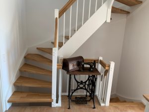 Escalier traditionnel en bois avec main courante et marches en chênes. Contre marche et limon laqué en blanc, ballustres bois