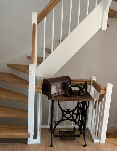 Escalier traditionnel en bois avec main courante et marches en chênes. Contre marche et limon laqué en blanc, ballustres bois