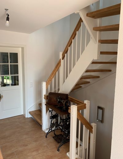 Escalier traditionnel en bois avec main courante et marches en chênes. Contre marche et limon laqué en blanc, ballustres bois