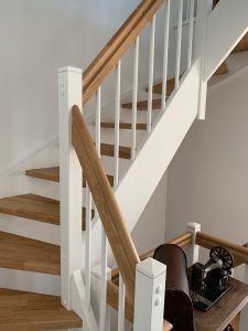 Escalier traditionnel en bois avec main courante et marches en chênes. Contre marche et limon laqué en blanc, ballustres bois