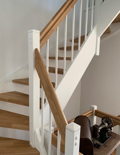 Escalier traditionnel en bois avec main courante et marches en chênes. Contre marche et limon laqué en blanc, ballustres bois