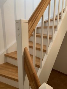 Escalier traditionnel en bois avec main courante et marches en chênes. Contre marche et limon laqué en blanc, ballustres bois