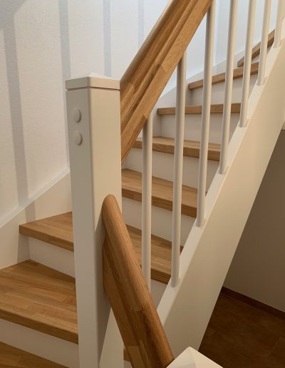 Escalier traditionnel en bois avec main courante et marches en chênes. Contre marche et limon laqué en blanc, ballustres bois