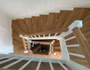 Escalier traditionnel en bois avec main courante et marches en chênes. Contre marche et limon laqué en blanc, ballustres bois