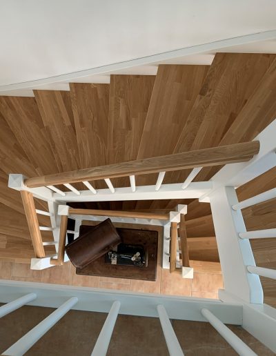Escalier traditionnel en bois avec main courante et marches en chênes. Contre marche et limon laqué en blanc, ballustres bois