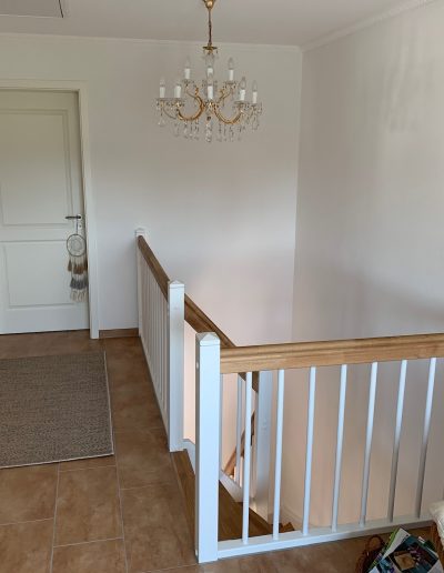 Escalier traditionnel en bois avec main courante et marches en chênes. Contre marche et limon laqué en blanc, ballustres bois