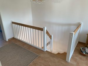 Escalier traditionnel en bois avec main courante et marches en chênes. Contre marche et limon laqué en blanc, ballustres bois