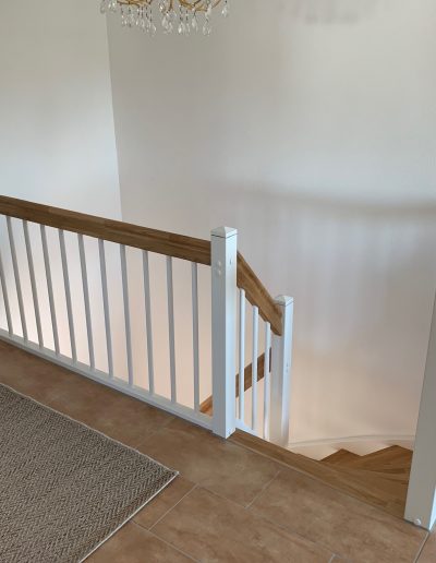 Escalier traditionnel en bois avec main courante et marches en chênes. Contre marche et limon laqué en blanc, ballustres bois
