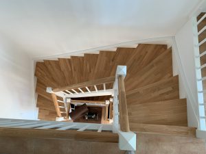 Escalier traditionnel en bois avec main courante et marches en chênes. Contre marche et limon laqué en blanc, ballustres bois