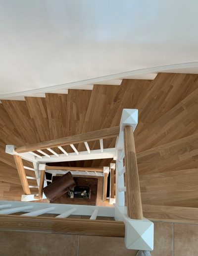 Escalier traditionnel en bois avec main courante et marches en chênes. Contre marche et limon laqué en blanc, ballustres bois