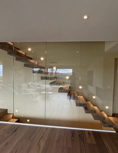 Garde-corps horizontal et rampant en full verre sans poteau apparant autour d'un escalier suspendu autoporteur design en bois