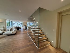 Garde-corps horizontal et rampant en full verre sans poteau apparant autour d'un escalier suspendu autoporteur design en bois