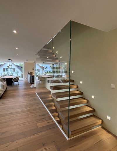 Garde-corps horizontal et rampant en full verre sans poteau apparant autour d'un escalier suspendu autoporteur design en bois
