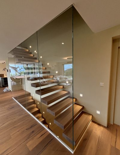 Garde-corps horizontal et rampant en full verre sans poteau apparant autour d'un escalier suspendu autoporteur design en bois