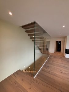 Garde-corps horizontal et rampant en full verre sans poteau apparant autour d'un escalier suspendu autoporteur design en bois