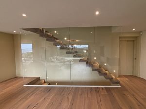 Garde-corps horizontal et rampant en full verre sans poteau apparant autour d'un escalier suspendu autoporteur design en bois