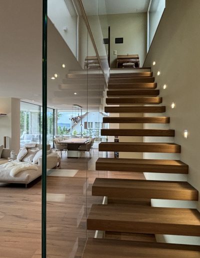 Garde-corps horizontal et rampant en full verre sans poteau apparant autour d'un escalier suspendu autoporteur design en bois