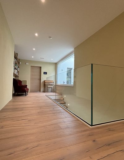 Garde-corps horizontal et rampant en full verre sans poteau apparant autour d'un escalier suspendu autoporteur design en bois