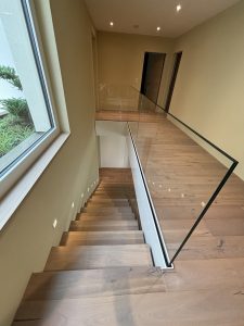 Garde-corps horizontal et rampant en full verre sans poteau apparant autour d'un escalier suspendu autoporteur design en bois