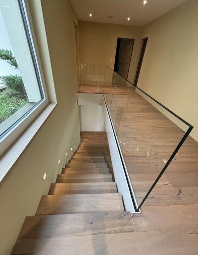 Garde-corps horizontal et rampant en full verre sans poteau apparant autour d'un escalier suspendu autoporteur design en bois