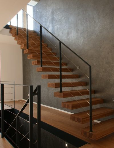 garde-corps rampant en acier plat laqué gris antracite et cable horizontal en inox autour d'une scalier autoporteur en bois