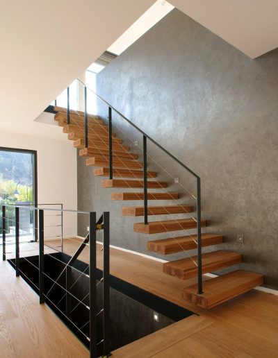 garde-corps horizontale autour de la trémie en acier plat laqué gris antracite et cable horizontal en inox autour d'une scalier autoporteur en bois