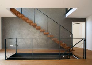 garde-corps horizontale autour de la trémie en acier plat laqué gris antracite et cable horizontal en inox autour d'une scalier autoporteur en bois