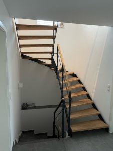Escalier moderne bois métal type industriel avec limon en acier laqué, garde-corps en fer plat et finition main courante bois soudé et remplissage cables inox et verre en aprtie basse