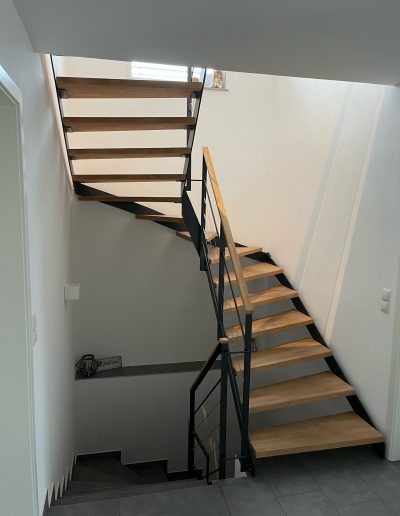 Escalier moderne bois métal type industriel avec limon en acier laqué, garde-corps en fer plat et finition main courante bois soudé et remplissage cables inox et verre en aprtie basse