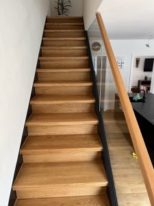 Escalier marche et contre marches en bois chêne entre limon bois laqué industriel et garde-corps en verre plein, finition main courante chêne, sans poteau