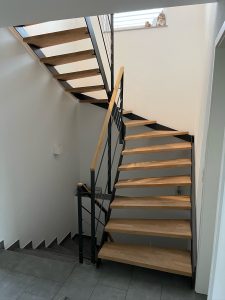 Escalier moderne bois métal type industriel avec limon en acier laqué, garde-corps en fer plat et finition main courante bois soudé et remplissage cables inox et verre en aprtie basse