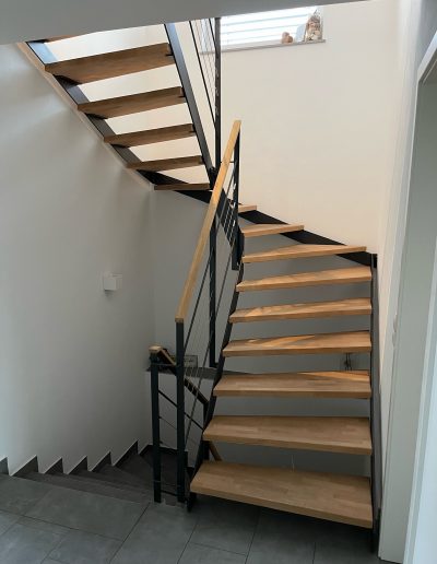 Escalier moderne bois métal type industriel avec limon en acier laqué, garde-corps en fer plat et finition main courante bois soudé et remplissage cables inox et verre en aprtie basse