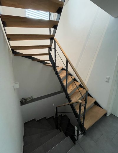 Escalier moderne bois métal type industriel avec limon en acier laqué, garde-corps en fer plat et finition main courante bois soudé et remplissage cables inox et verre en aprtie basse
