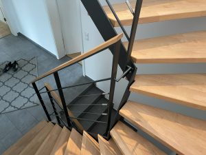 Escalier moderne bois métal type industriel avec limon en acier laqué, garde-corps en fer plat et finition main courante bois soudé et remplissage cables inox et verre en aprtie basse