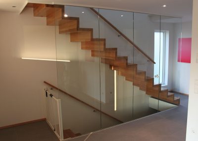 Escalier design marche contremarches à Ertsein: design piano, du bois noble, un garde-corps en verre plein sans poteaux