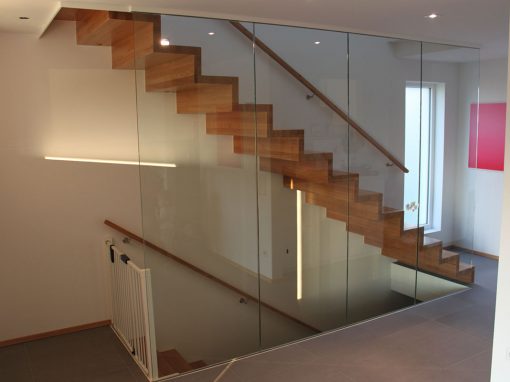 Escalier design marche contremarches à Ertsein: design piano, du bois noble, un garde-corps en verre plein sans poteaux