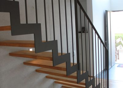 Escalier design à Dettwiller : limon crémaillère en acier gris marche aboutée en chêne et garde-corps en acie rplat avec barreaudage verticale laqué gris