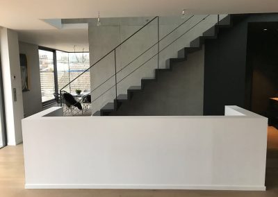 Escalier laqué noir à Hundsbach : Garde-corps rampant en acier laqué, pallier en verre, muret blanc et escalier marche contremarche